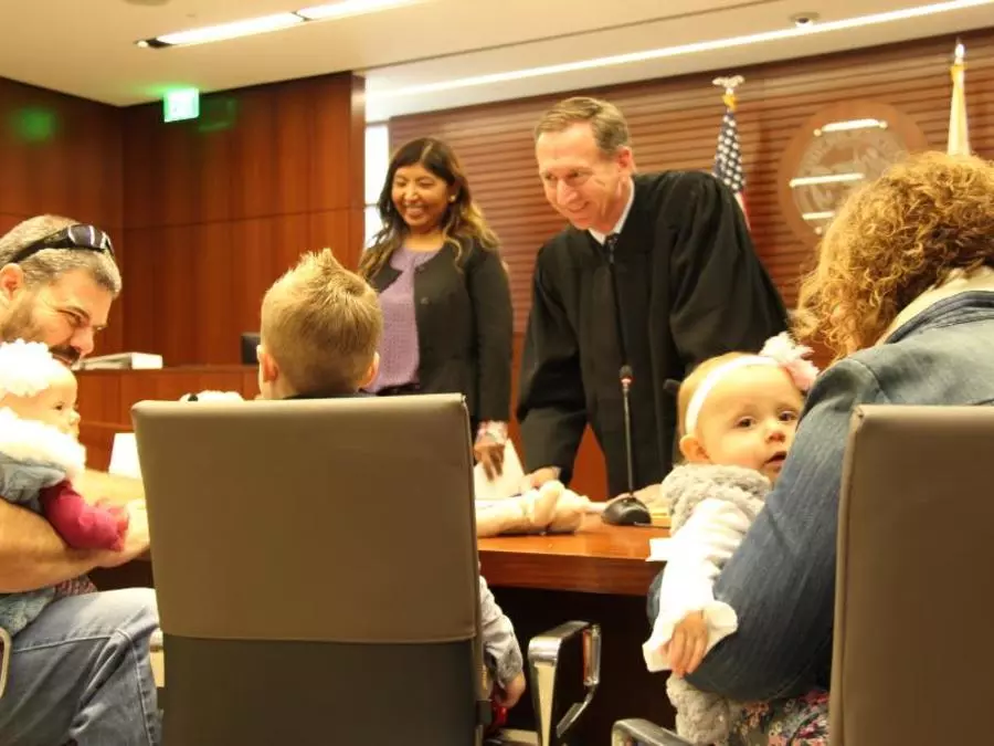 Presiding Judge Theodore C. Zayner signs paperwork to make the adoption legal